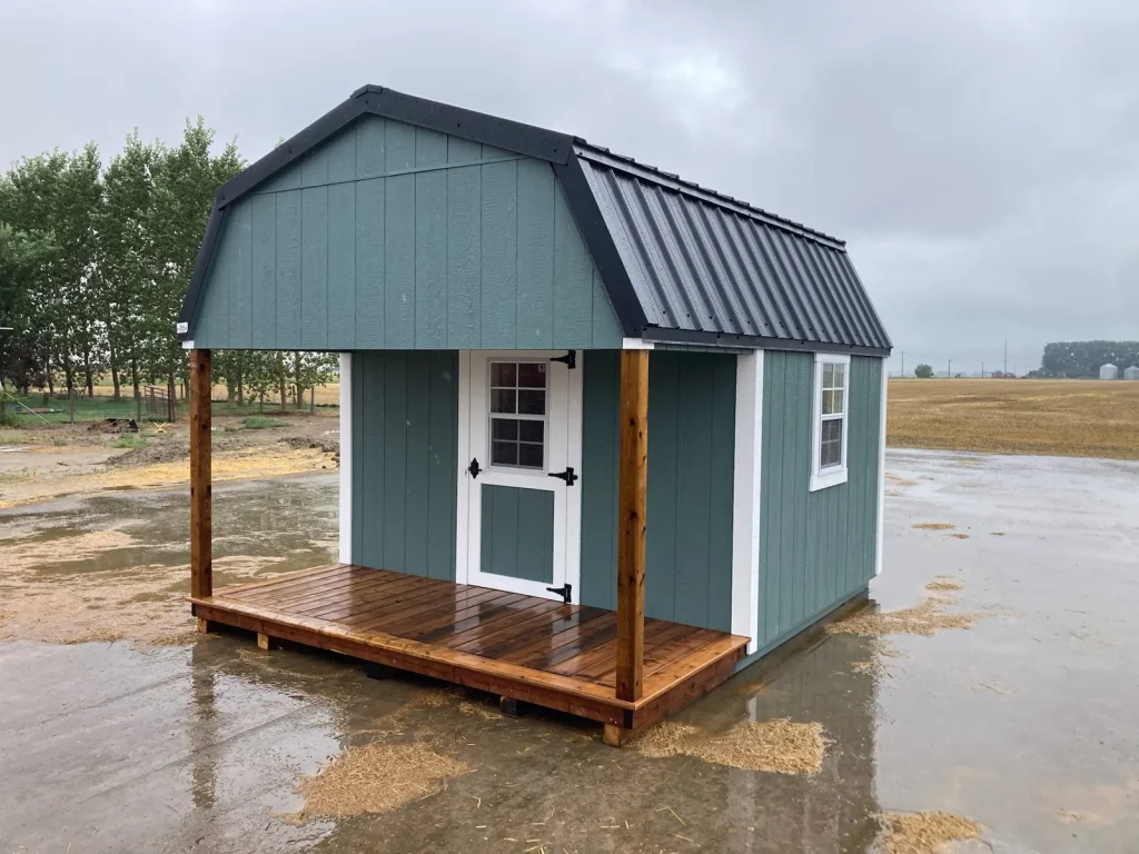 Custom playhouse by Fox Buildings with a gambrel metal roof, covered cedar porch and white trim, ready for delivery near Lethbridge